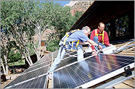 Photo showing two men inspecting solar panels on a roof.